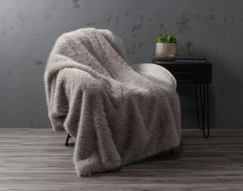 Our ______ Arctic Fox Throw draped over  the left side of a couch with its faux fur surface face-up.