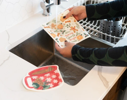 Angled view of someone neatly rinsing our Baking Bright Swedish Dishcloths in a sink.