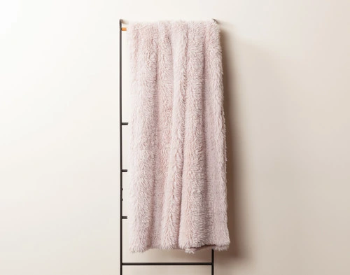 Front view of our Pink Soft Mink Throw draped over a tall rack against an empty white wall.