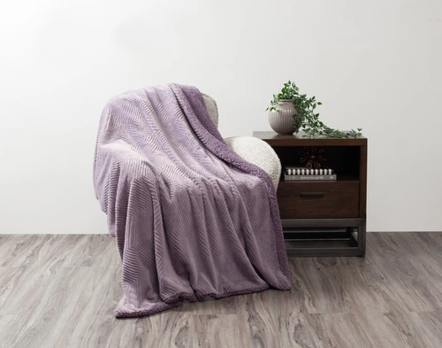 Front view of our Purple Sage Chevron Etch Throw draped over a small chair in a simple living room.