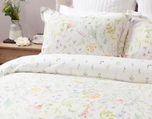 The Lena Duvet Cover and matching Pillow Shams at the head of a simple bed shown at a side angle. 