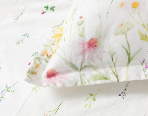 Close up of the Lena Pillow Sham corner featuring its matching self flange border atop the Lena Duvet Cover.