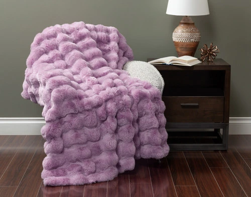 Front view of our Purple Bubble Faux Fur Throw draped over a small armchair in a green fall living room.