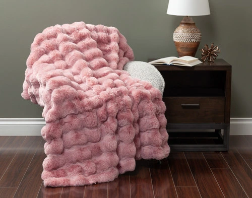 Front view of our Pink Bubble Faux Fur Throw draped over a small armchair in a green fall living room.