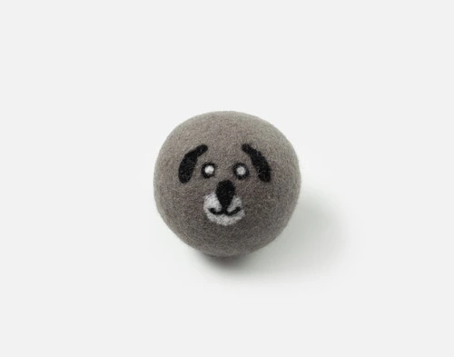 Vue de face de notre boule de séchage en laine brodée Buddy, posée sur une surface blanche solide.