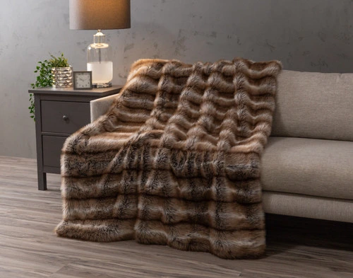 Angled view of our Mink Sable Faux Fur Throw draped over a couch in a modern living room.