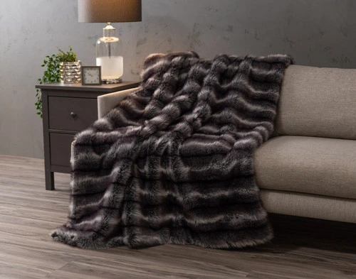 Angled view of our Onyx Sable Faux Fur Throw draped over a couch in a modern living room.