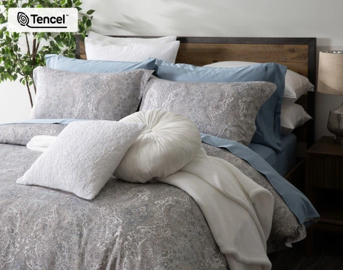 Vue en angle de notre collection Bayview habillant un lit queen avec des draps bleus et des accessoires en blanc.