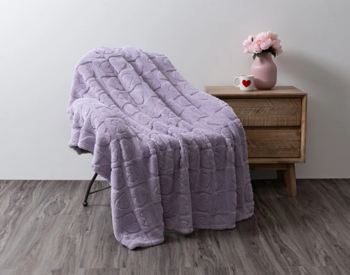 The Etched Hearts Fleece Throw draped over a chair in a simple room.