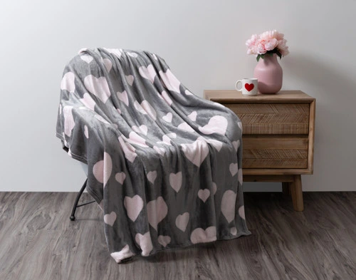 The Blushing Hearts Fleece Throw draped over a chair in a simple room.