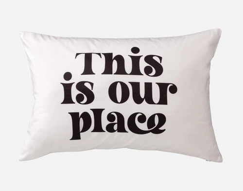 Front view of a pillowcase reading "This is our place" in large black font over a white surface.