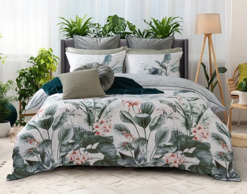 Front view of our Yolanda Duvet Cover dressed over a queen bed in front of several leafy green potted plants.