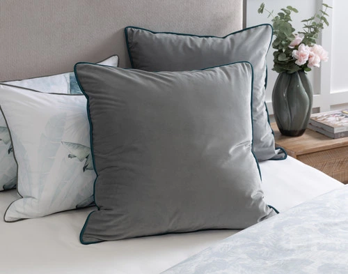 Angled view of our Yolanda Euro Sham sitting against other pillows at the headboard of a half-dressed white bed.