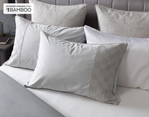 Angled view of our Marco Pillow Sham resting on a white bed against coordinating pillows.