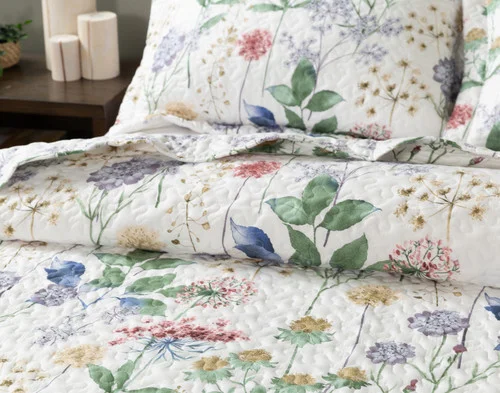 Off-centre, angled view of our Danielle Coverlet Set dressing the head of a bed in a simple bedroom.