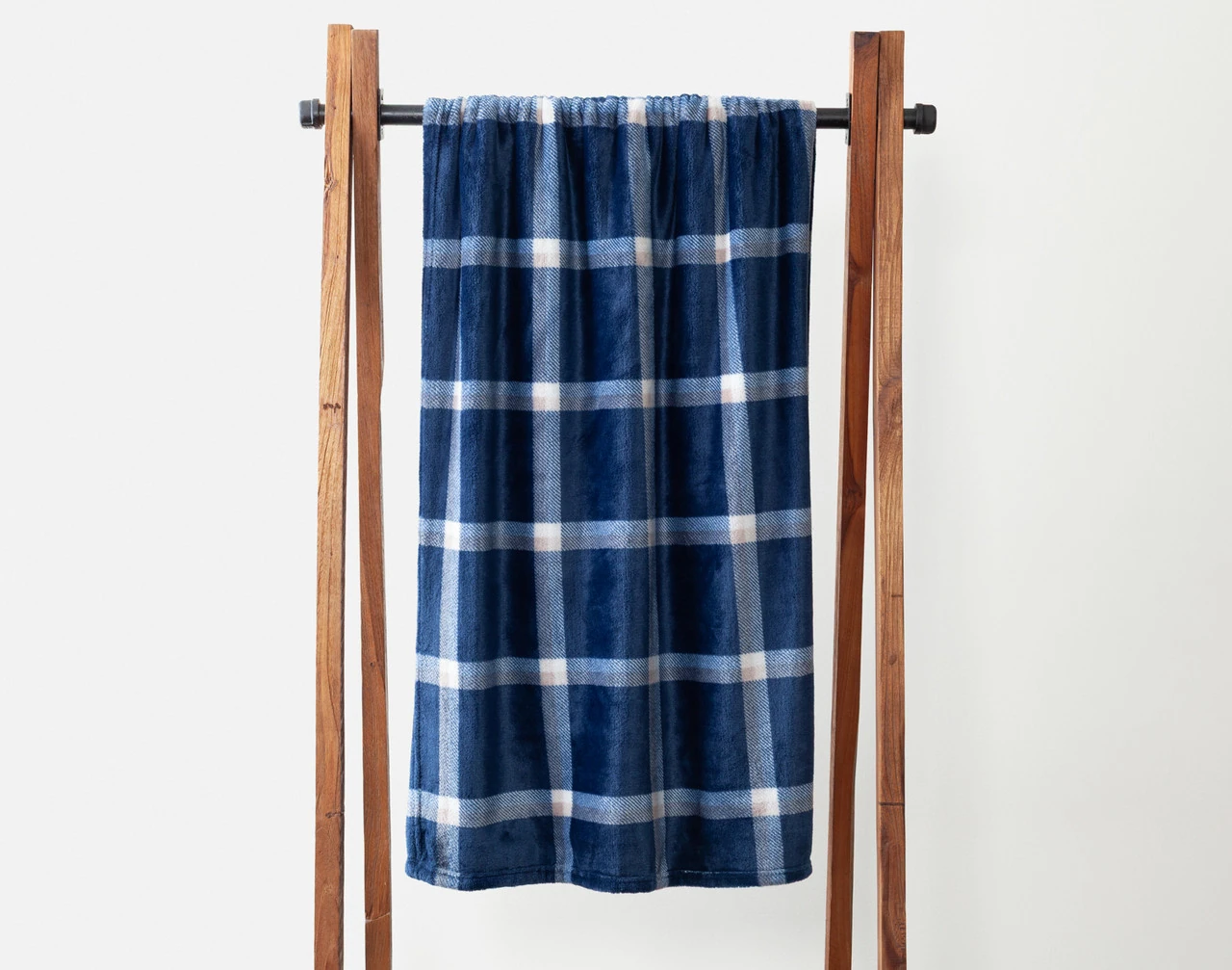Our Navywood Plaid Fleece Throw draped over a wooden hanger.