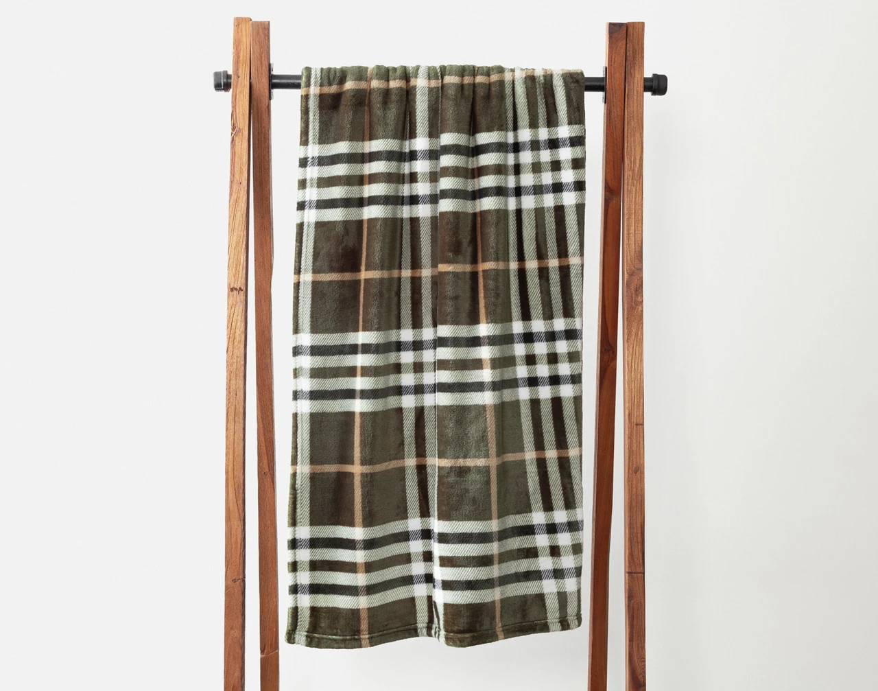 Our Pinecrest Plaid Fleece Throw draped over a wooden hanger.