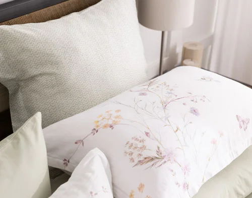 Our Elysium Pillow Sham styled at the head of a bed with green accessories.