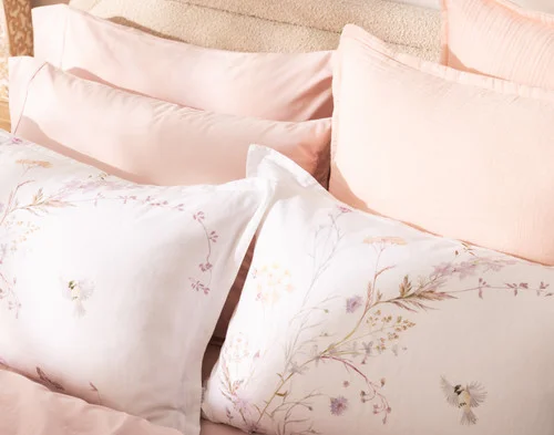 Our Elysium Pillow Shams styled at the head of a bed with pink accessories.