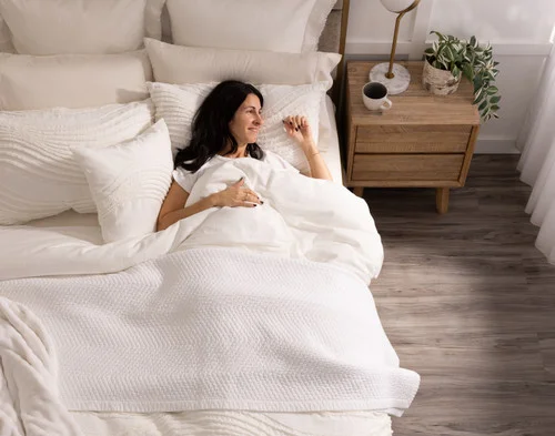 Woman sleeping in a bed dressed in our Savary collection.