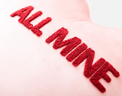 Close-up view of the tufted text on our All Mine Candy Heart Cushion.