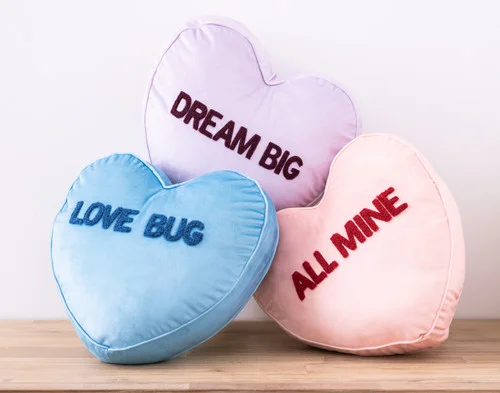 Our Dream Big, Love Bug, and All Mine Candy Heart Cushions resting in a small pile.