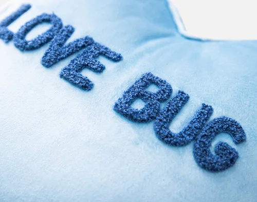 Close-up view of the tufted text on our Love Bug Candy Heart Cushion.