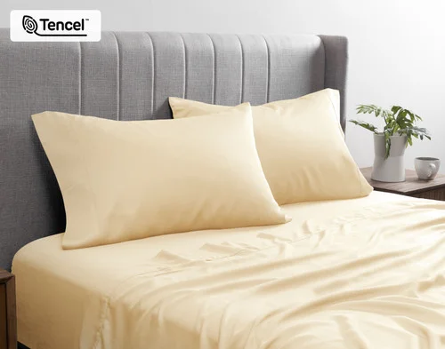Front view of our BeechBliss TENCEL™ Modal Pillowcase in Cornsilk resting against a headboard in a bed with matching sheets.