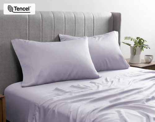 Front view of our BeechBliss TENCEL™ Modal Pillowcase in Lavender resting against a headboard in a bed with matching sheets.