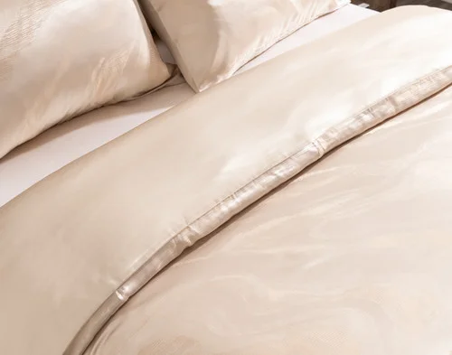 Angled view of our Solace Silk Blend Duvet Cover Set dressed over a plain bed.