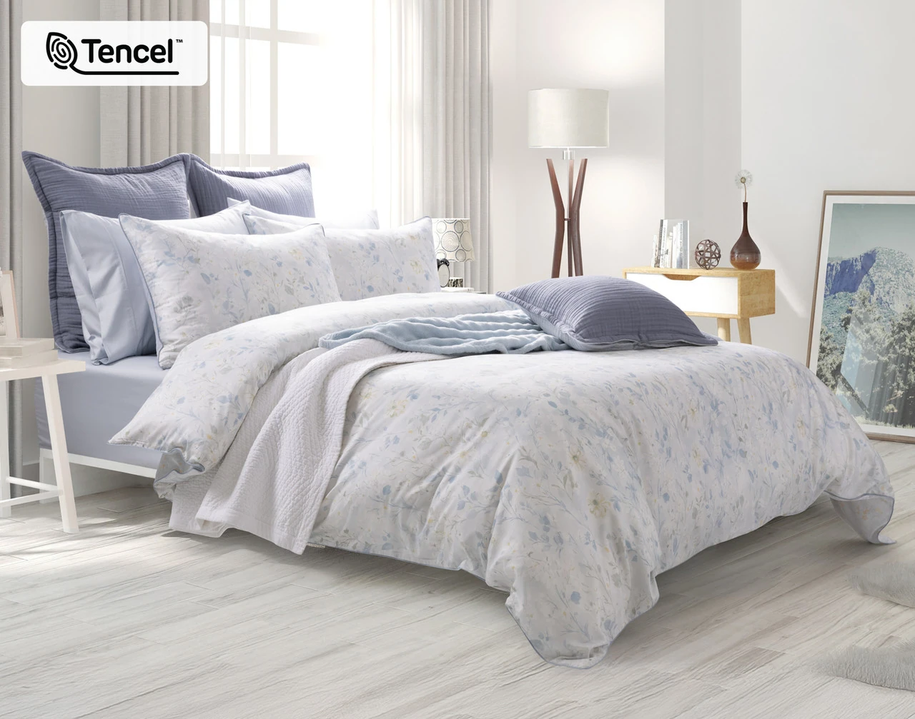 Angled view of our Josephine Duvet Cover dressing a queen bed with blue accessories.