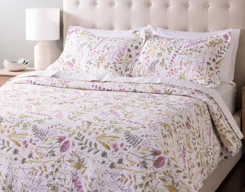 Angled view of our Zoey Cotton Quilt Set dressed over an empty queen bed.