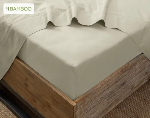 The corner of a bed with our Bamboo Cotton Flat Sheet in Thistle atop our Bamboo Cotton Fitted Sheet in Thyme.