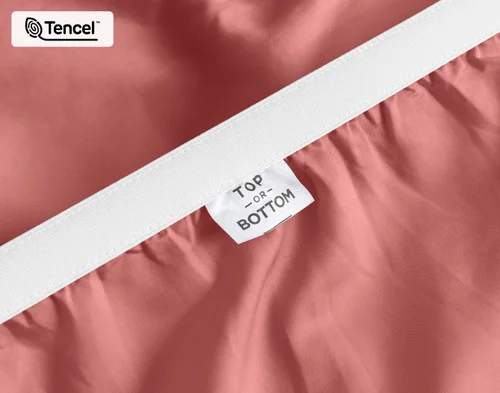 Close-up on the stretched elastic edge and tag stating "Top / Bottom" on our Eucalyptus Luxe TENCEL™ Lyocell Fitted Sheet in Raspberry Ice.