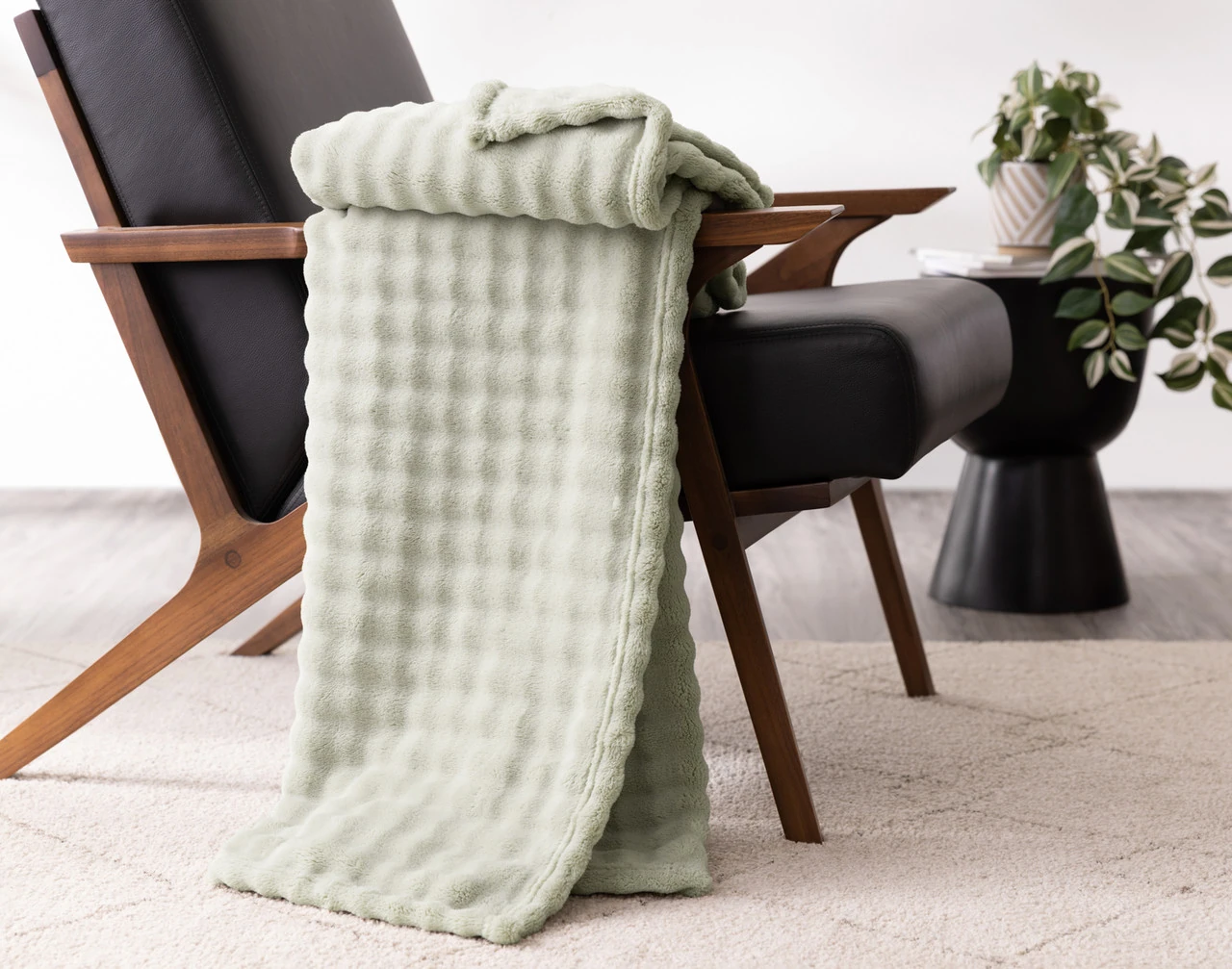 Our Sage Bubble Breeze Throw draped over the arm of a black chair.