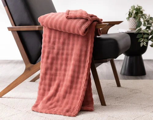 Our Potpourri Bubble Breeze Throw draped over the arm of a black chair.