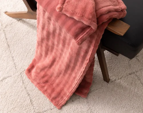 Angled view of our Potpourri Bubble Breeze Throw draped over a chair touching the floor.