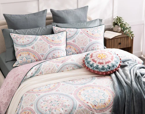 Angled view of our Mandira Duvet Cover Set dressing a queen bed with blue accessories.