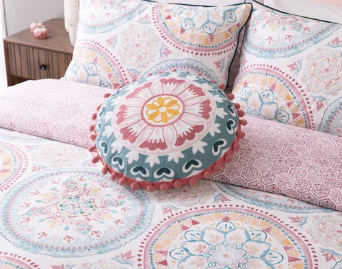 Our Mandira Round Cushion decorating the head of a bed with our Mandira Collection.