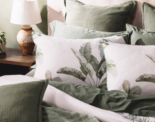 Angled view of our Sail Away Pillow Shams dressing the head of a bed with green accessories.
