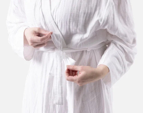 Close-up of two hands tying the belt on our Bamboo Cotton Gauze Bathrobe in White.