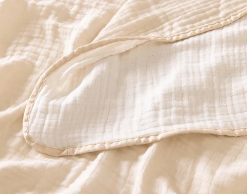 Close up on the textured surface of our Bamboo Gauze Throw in Bone.