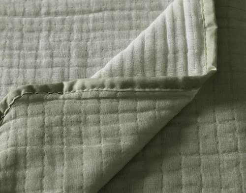 Close up on the folded surface of our Bamboo Gauze Throw in Leaf.