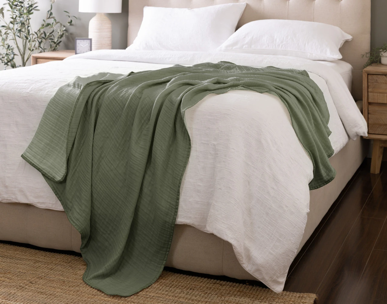 Our Bamboo Gauze Throw in Leaf draped over the corner of a bed.