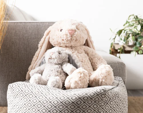Our large and small Easter Plush Bunny Cushions sitting together on a stool.