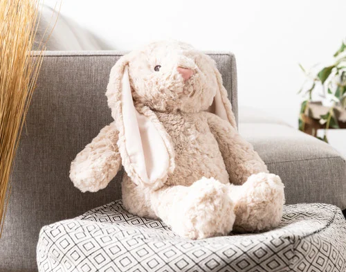 Our Large Easter Plush Bunny Cushion sitting on a couch stool.