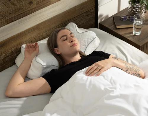 Woman resting comfortably on her back in bed on a Butterfly Memory Foam Pillow.