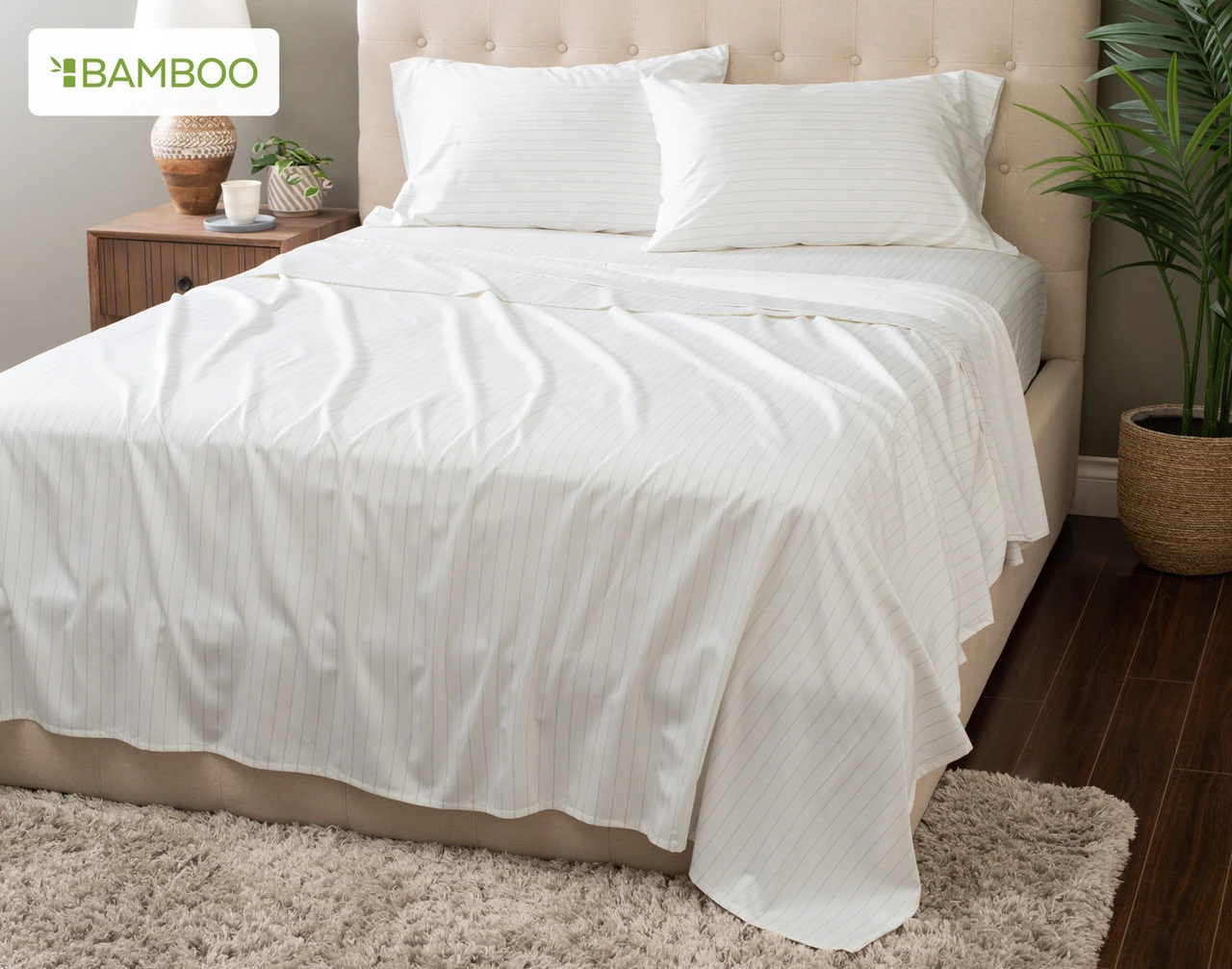 Angled view of our Bamboo Cotton Sheet Set in Ocean Stripe dressing a bed in a simple bedroom.