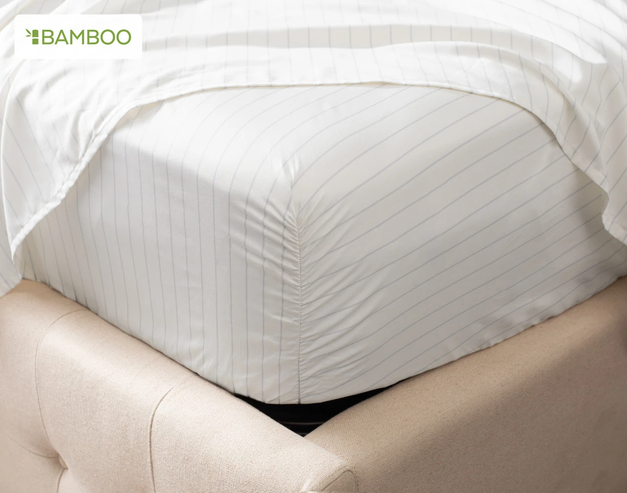 Our Bamboo Cotton Fitted Sheet in Ocean Stripe at the corner of a bed.