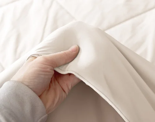 Hand feeling the edge of our Cloudstone Cool Touch Blanket's soft surface.